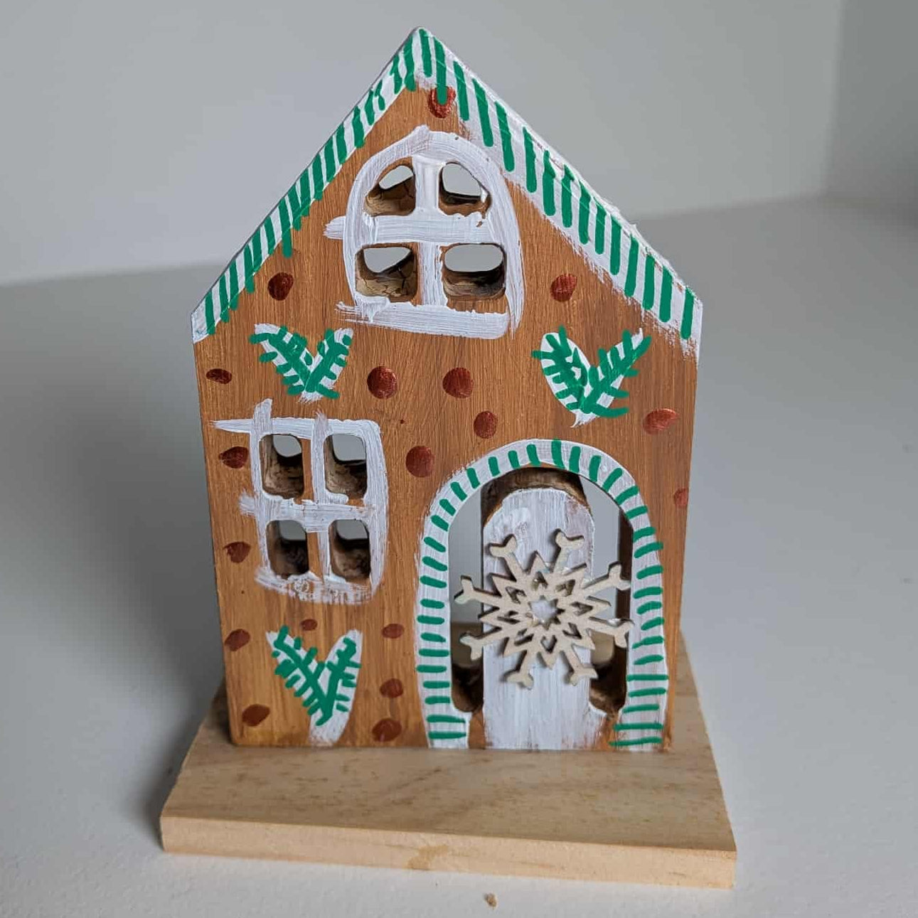 Wooden house ornament with decorative elements on a plain background